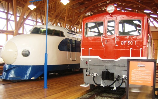 西条市にある四国鉄道文化館の写真です。白と青のツートンカラーの「新幹線0系」と赤と、灰色の「DF50型ディーゼル機関車」が写っています。