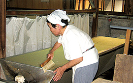 内子に在る「天神産紙工場」の写真です。女性が手作業で紙すきしています。